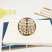 Circular brass seal with white Lu prosperity symbol design on white stationery and navy paper