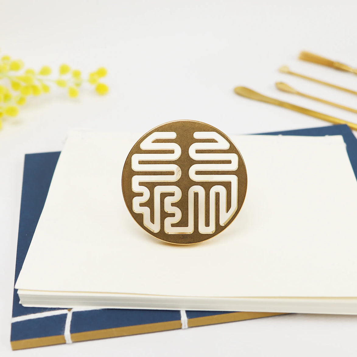 Circular brass seal with white Lu prosperity symbol design on white stationery and navy paper