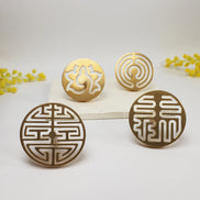 Four circular brass incense seals with lotus flower and geometric cutout patterns on white surface