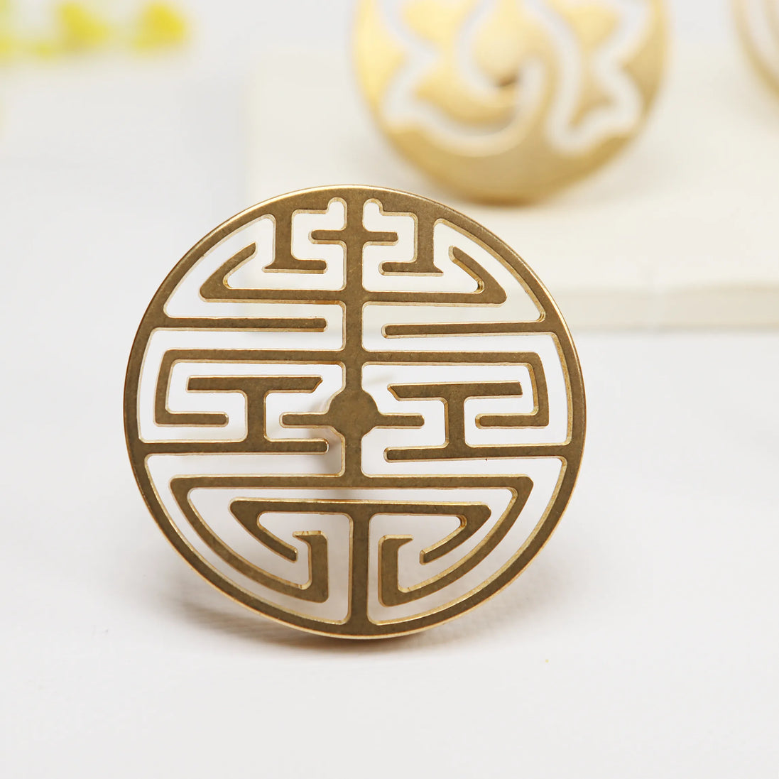 Circular brass seal with traditional Double Happiness Chinese symbol in geometric cutout design on white surface