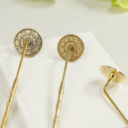 Golden brass incense sealing stamp with round head next to translucent amber decorative holder on white surface