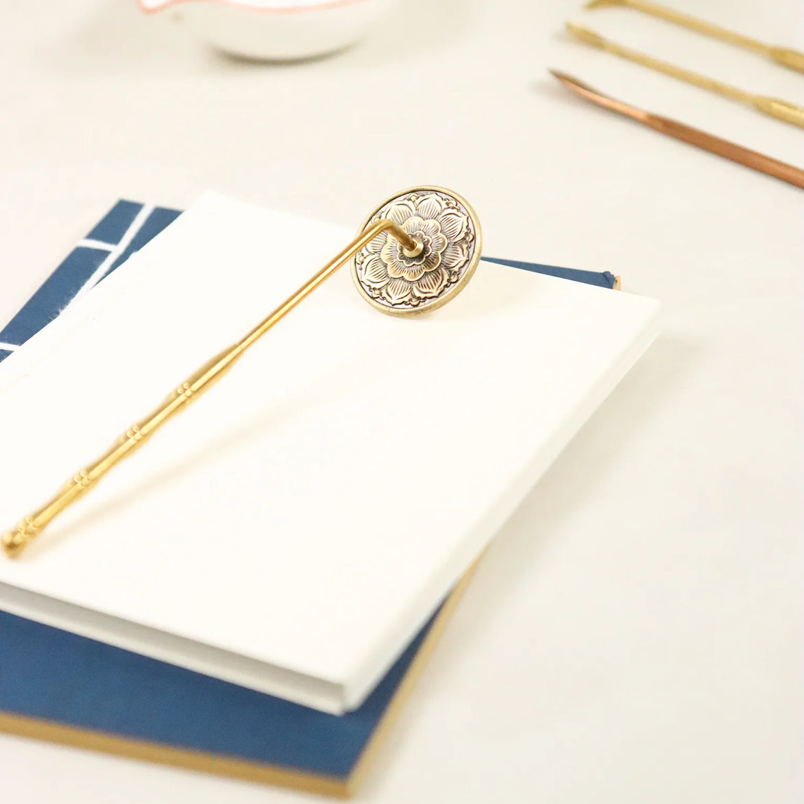 Golden brass stamp with carved lotus flower design on handle, positioned on white notebook pages
