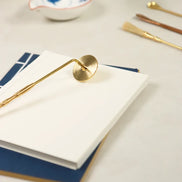 Brass incense sealing stamp with circular head and long handle on white paper and blue surface
