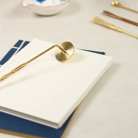 Brass incense sealing stamp with circular head and long handle on white paper and blue surface