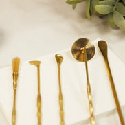 Five brass incense sealing tools laid out on white surface including lotus stamp, brush, spade, spoon and scoop