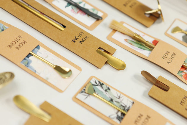 Brass incense tools set with lotus stamp designs arranged on kraft paper packaging showing various ceremonial tools