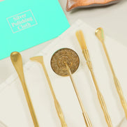 Turquoise silver polishing cloth next to golden brass tools and utensils on white marble surface