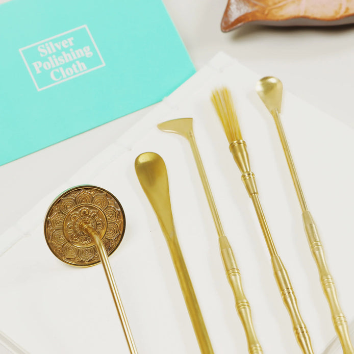 Turquoise silver polishing cloth next to golden brass tools on white surface for metal maintenance