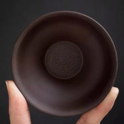 Purple clay tea strainer with fine mesh filter held in hand showing interior detail