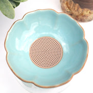 Turquoise ceramic tea strainer bowl with gold rim and perforated base for loose leaf tea